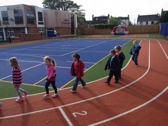 children lined up on synthetic running track