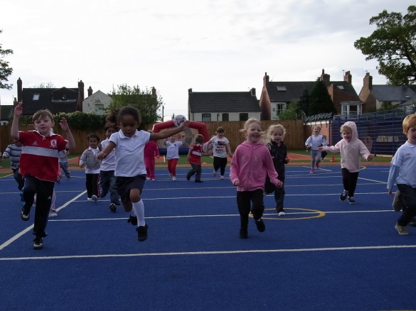 primary school pupils playing on blue muga